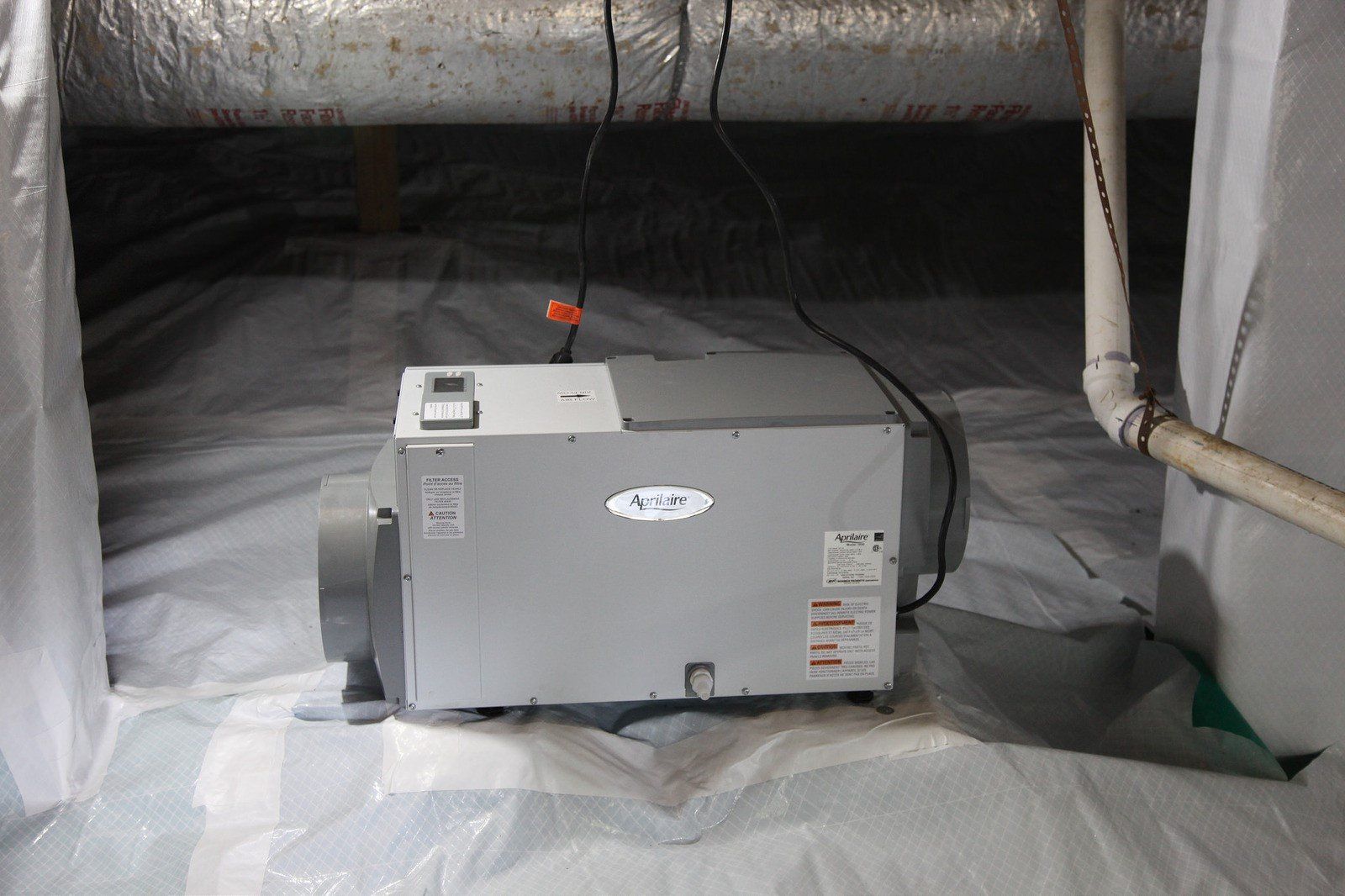 A machine is sitting in a basement next to a pipe.
