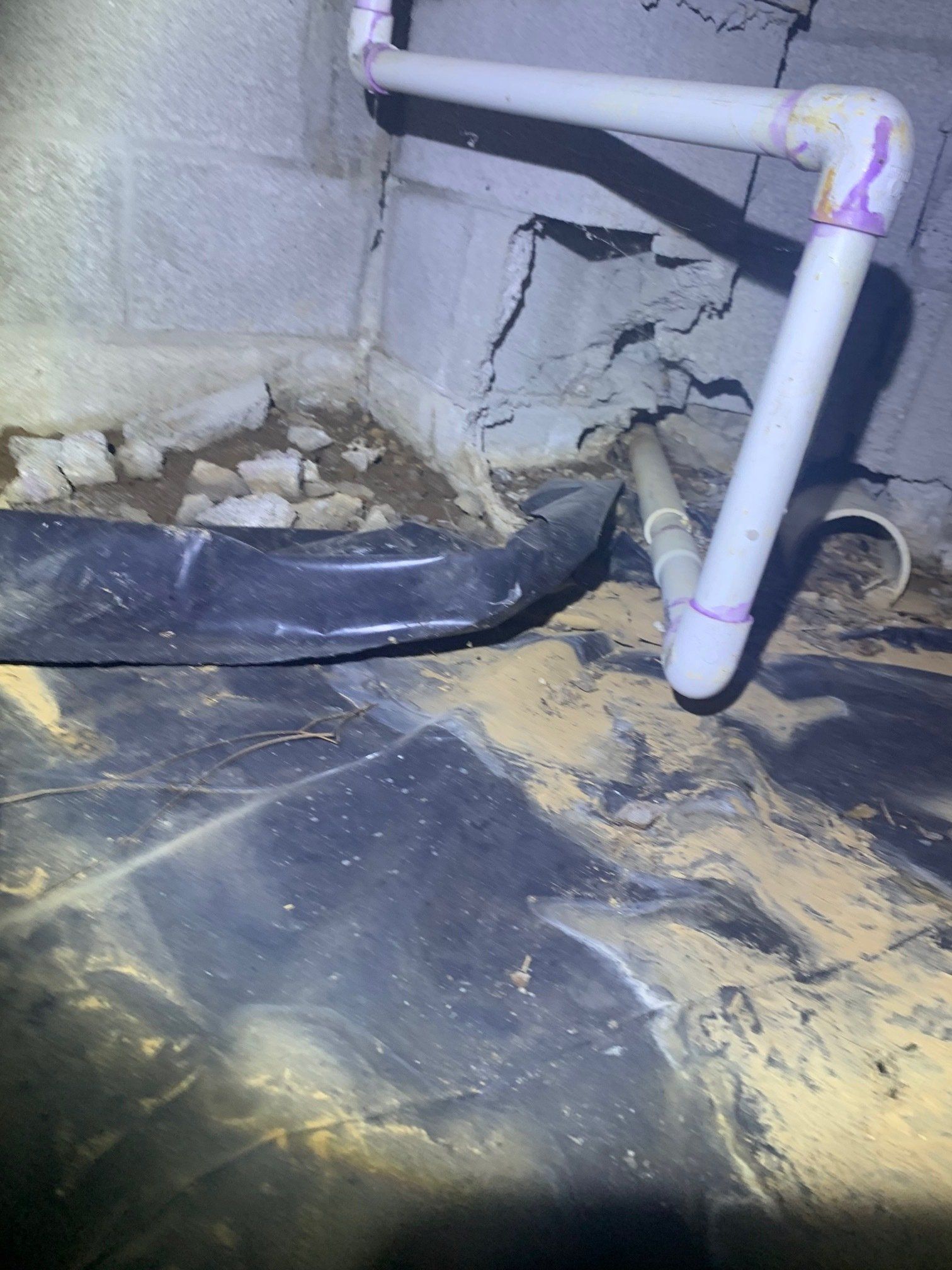 A close up of a pipe in a basement with a brick wall in the background.