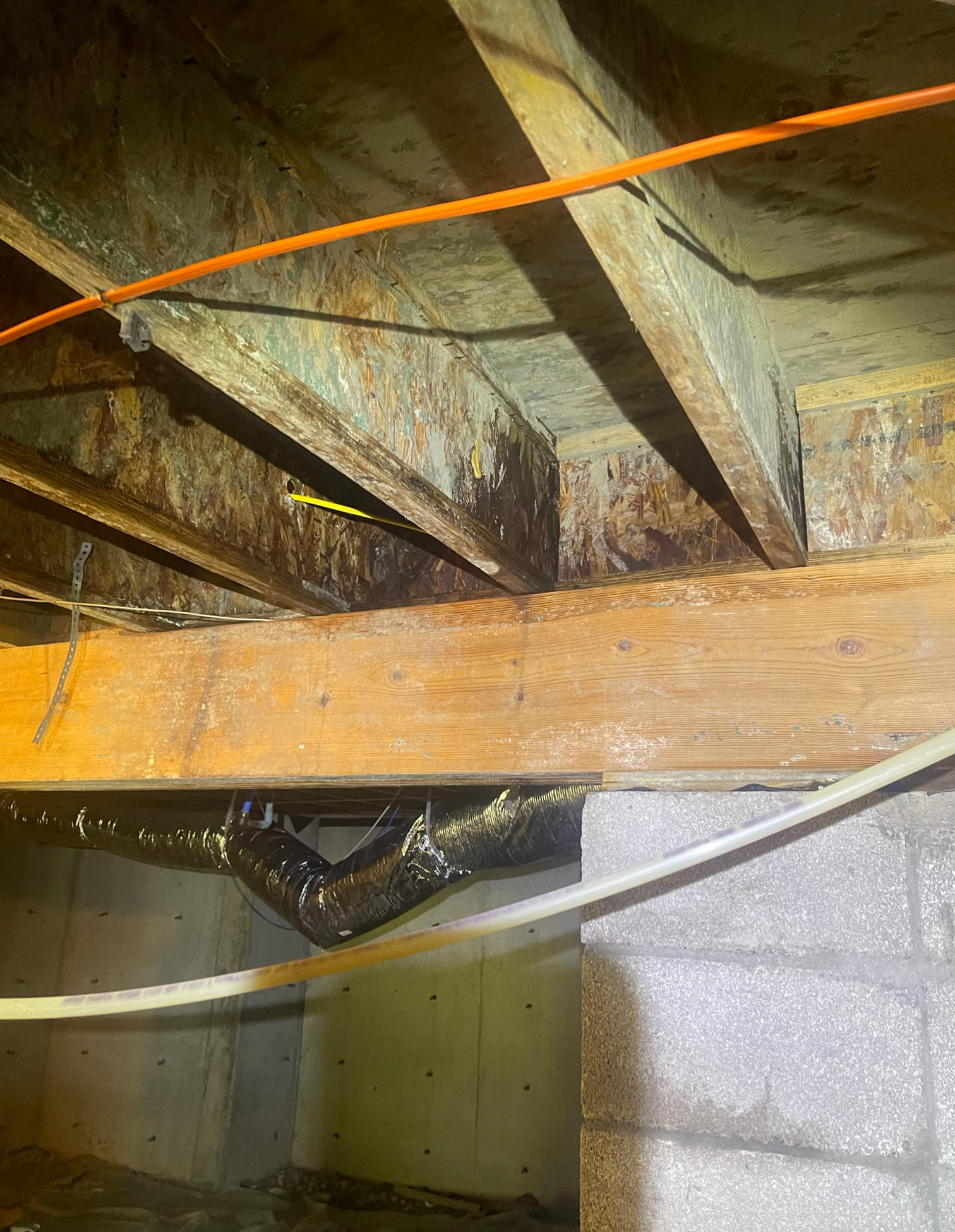 A wooden beam is hanging from the ceiling of a basement.