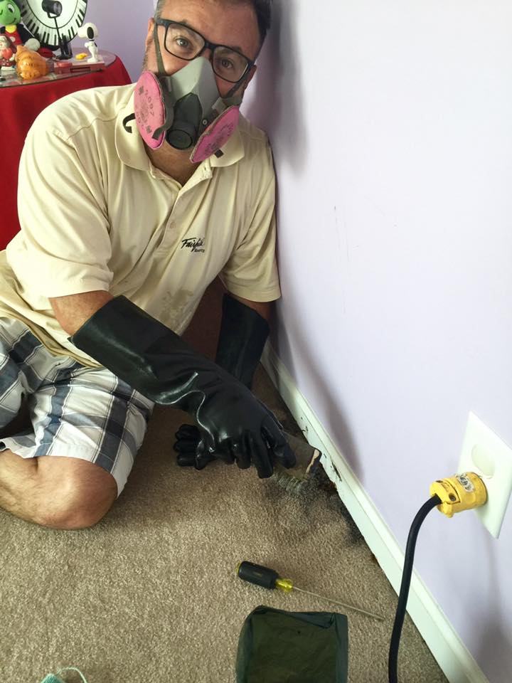 A man wearing a gas mask and gloves is working on a wall