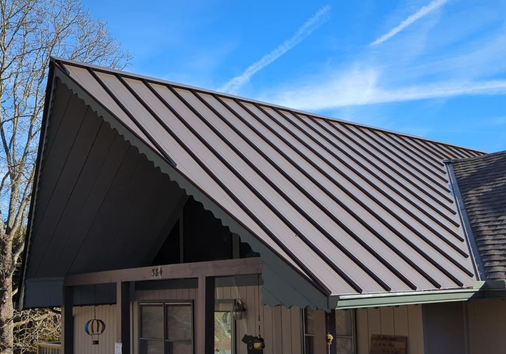 Brown metal roof on a house with a blue sky background. The roof has a decorative edge.