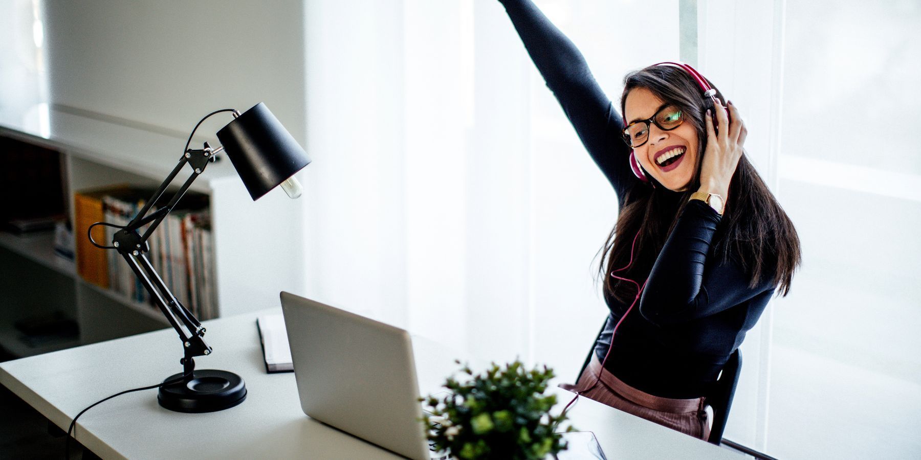 A woman is sitting at a desk with her arms in the air.