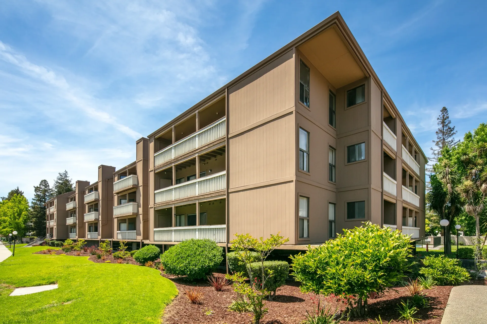 Exterior view of apartment building with balconies and manicured lawn.