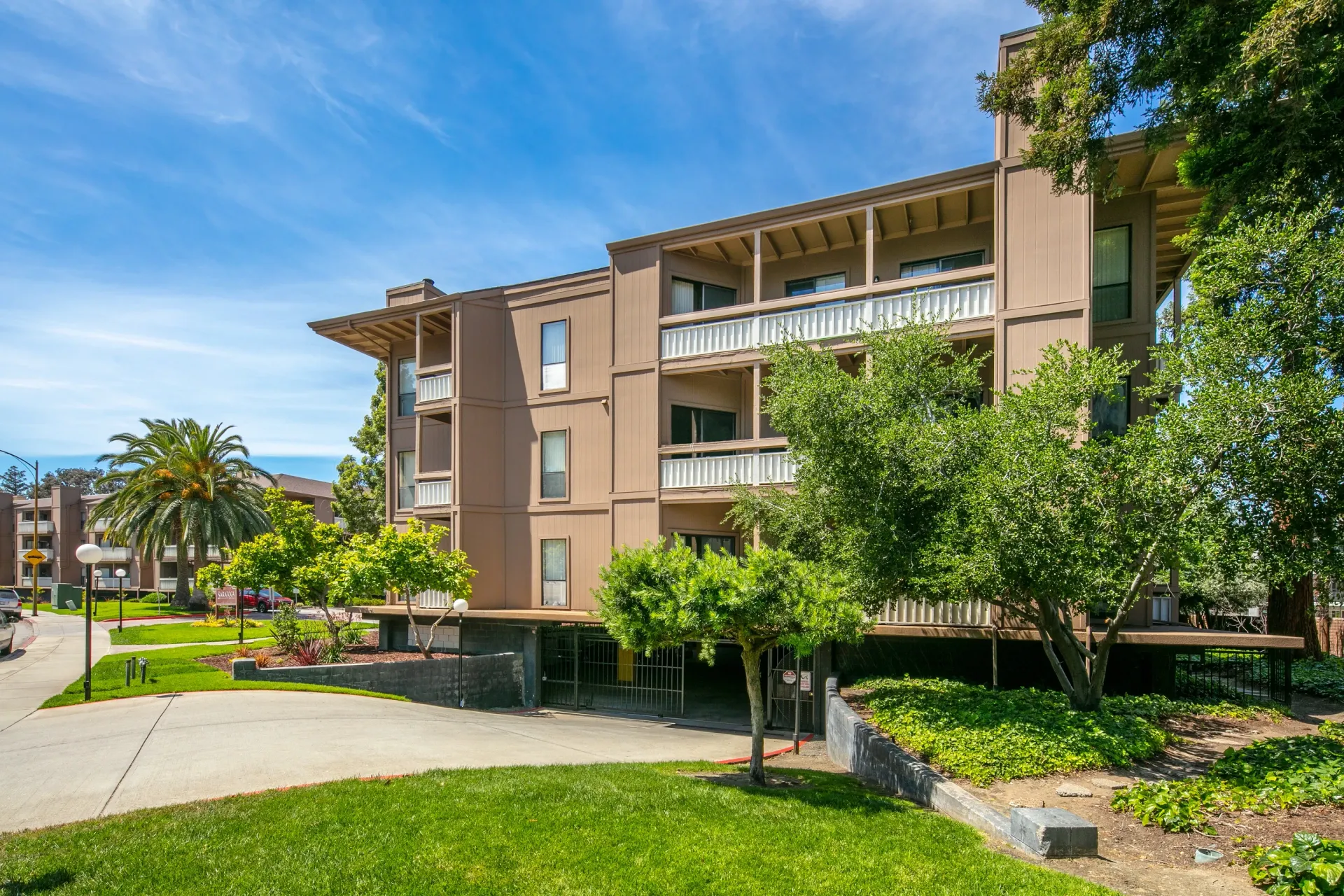 Exterior view of a multifamily apartment building with balconies and lush landscaping.