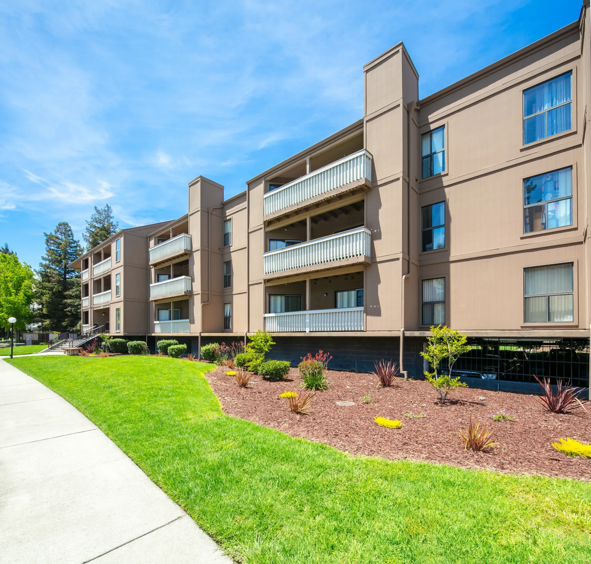 Exterior view of apartment building with balconies and surrounding green lawn.