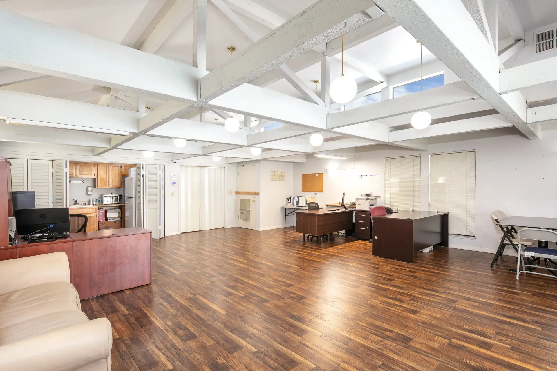 Open office space with desks, chairs, and a small kitchen area.
