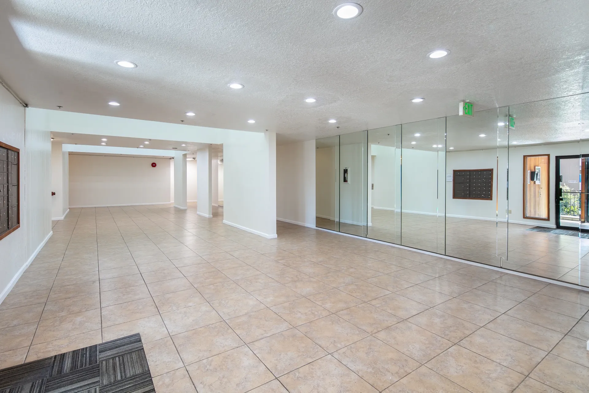 Large tiled entryway with mirrored walls and mailboxes.