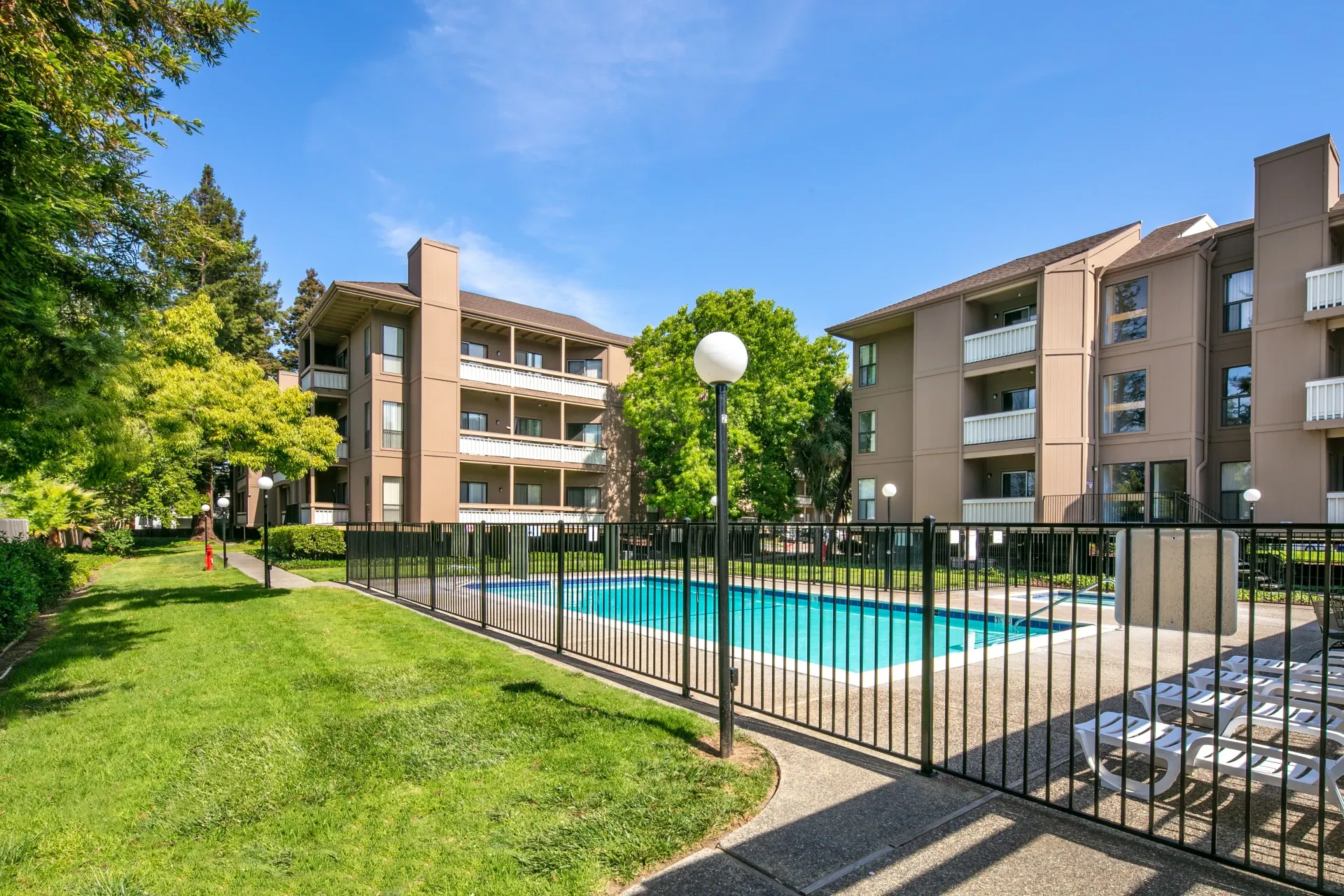 Apartment building exterior with a swimming pool and lounge chairs