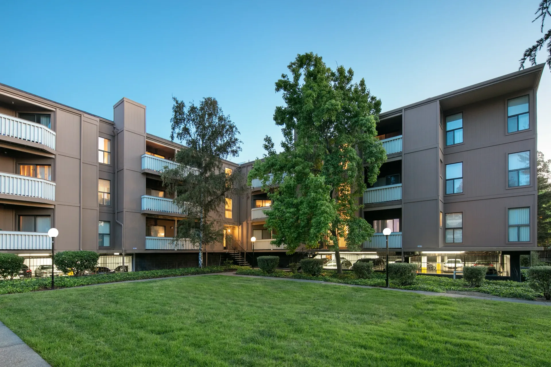 Exterior view of an apartment building with balconies and a manicured lawn.