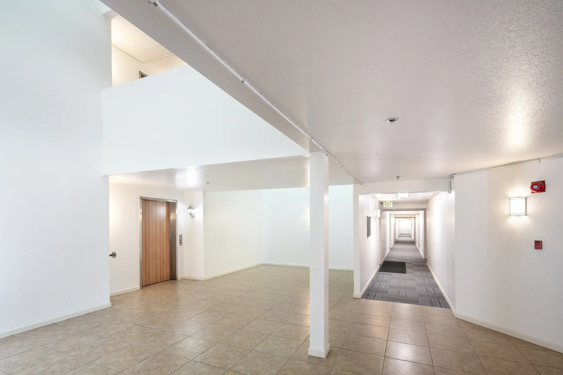 Interior hallway with elevator and tiled flooring.