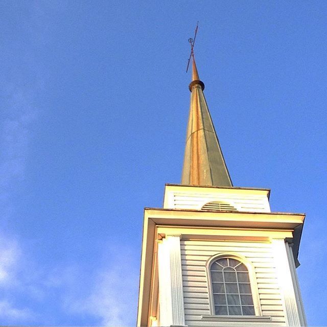White church steeple with tall spire against a clear blue sky