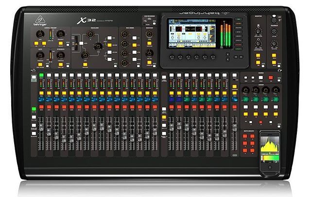 Digital audio mixing console with many sliders, knobs, and a central display screen