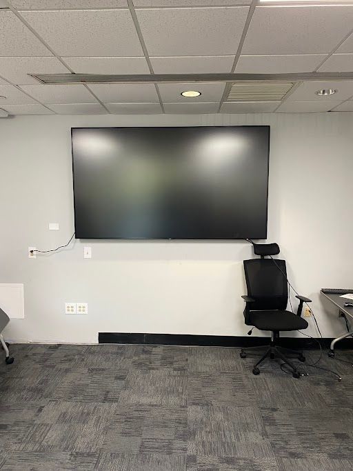 Conference room with wall-mounted TV, black chair, and carpeted floor