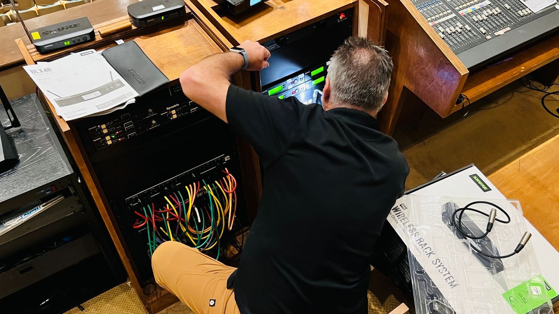 Person working on cables inside an open desktop computer tower at a desk
