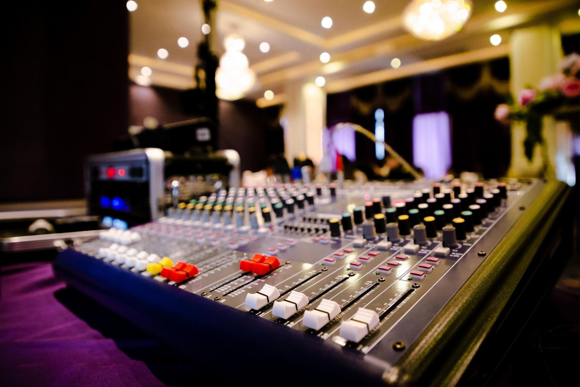 Audio mixing console with sliders and knobs in a dimly lit event venue