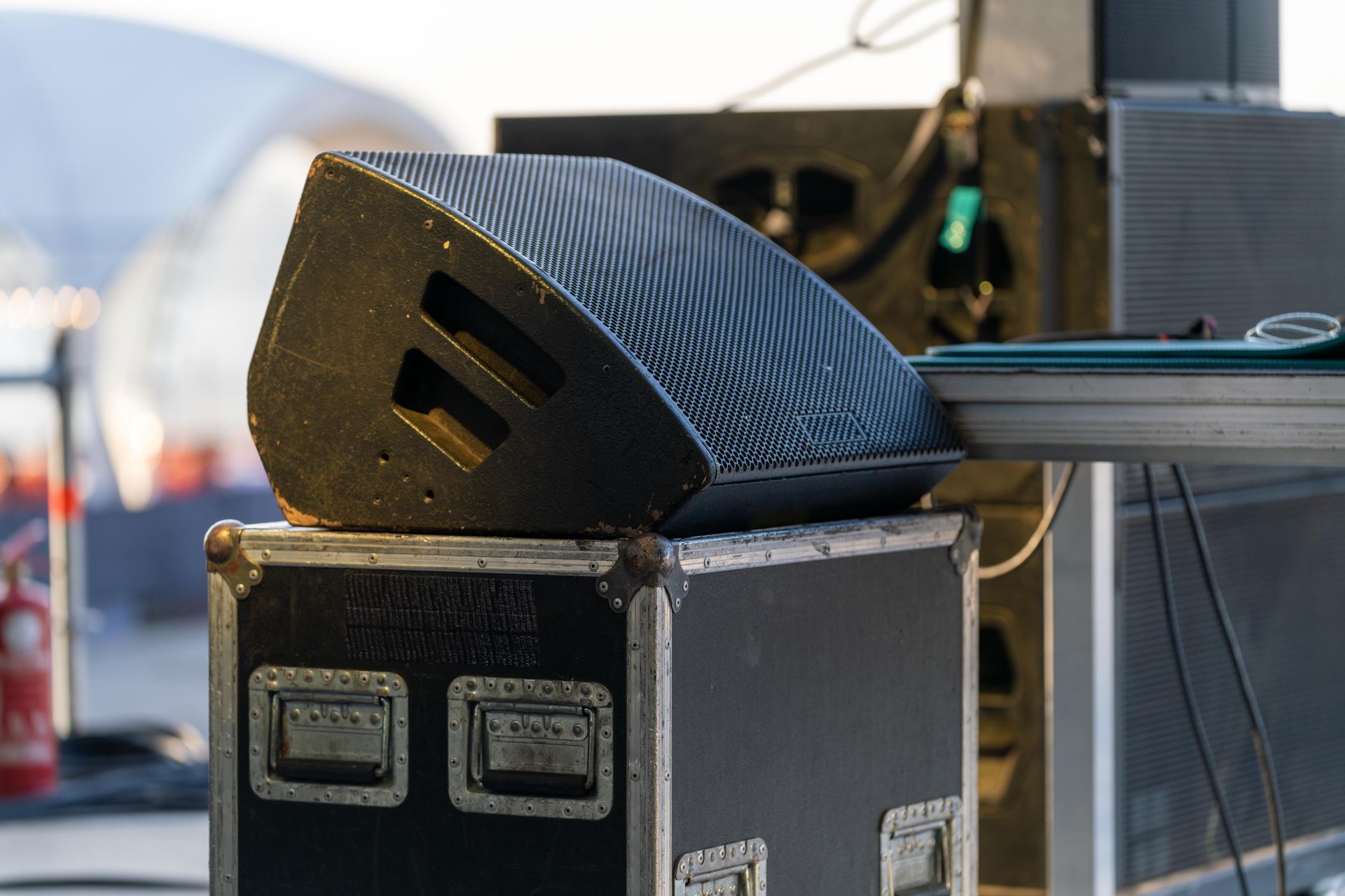 Black textured speaker cabinet on a stage road case with other audio gear in the background