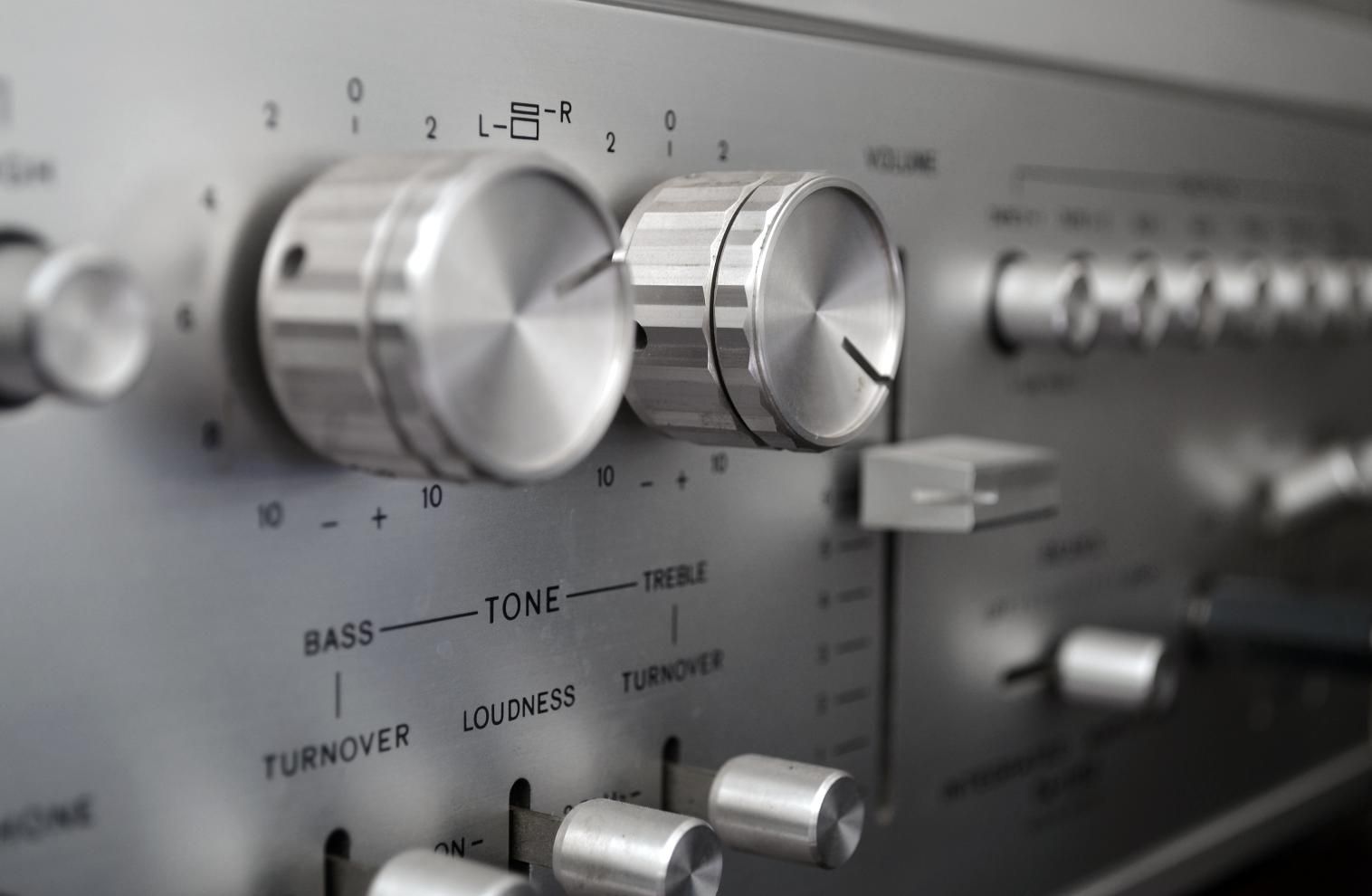 Close-up of a silver stereo receiver with large dials and knobs on a brushed metal faceplate