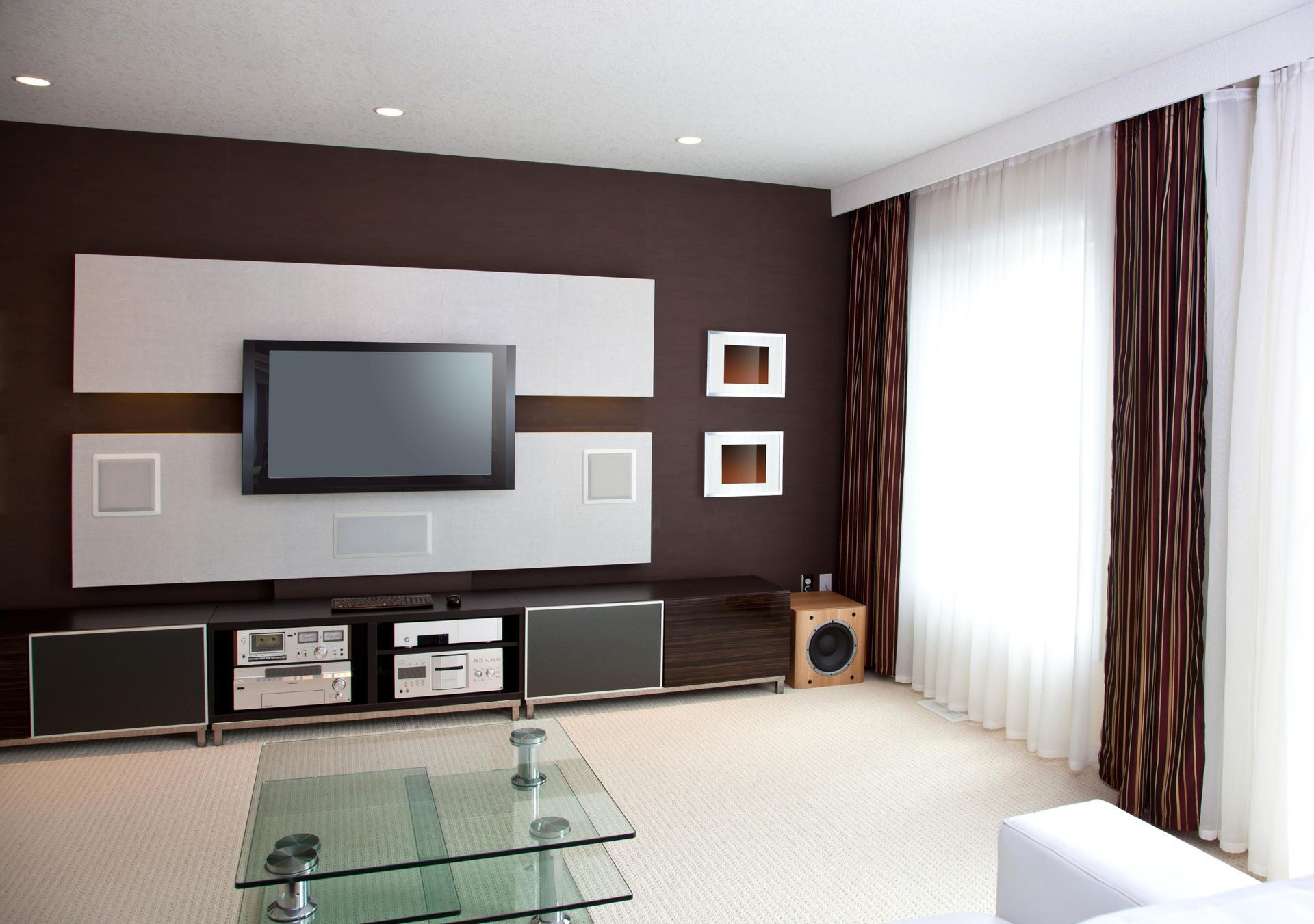 Modern living room with wall-mounted TV, dark accent wall, glass coffee table, and sheer curtains