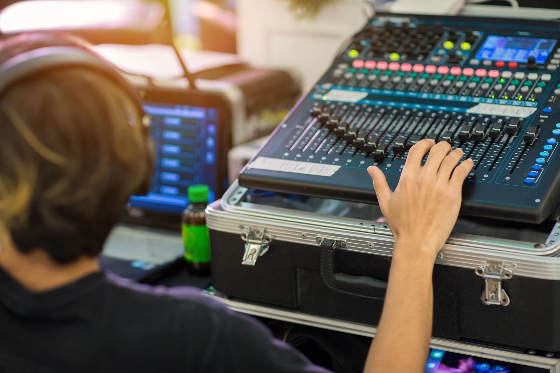 Person adjusting controls on a digital audio mixing console in a live sound setup