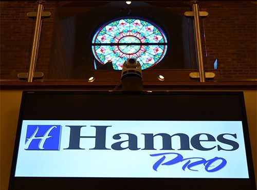 Hames Pro sign beneath a stained-glass window in a church interior