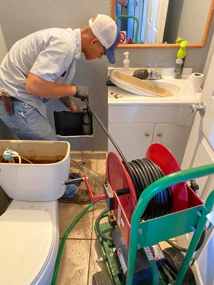 Fast Track Plumbing technician performing Drain Services Spring TX with a drain snake under a bathroom sink.