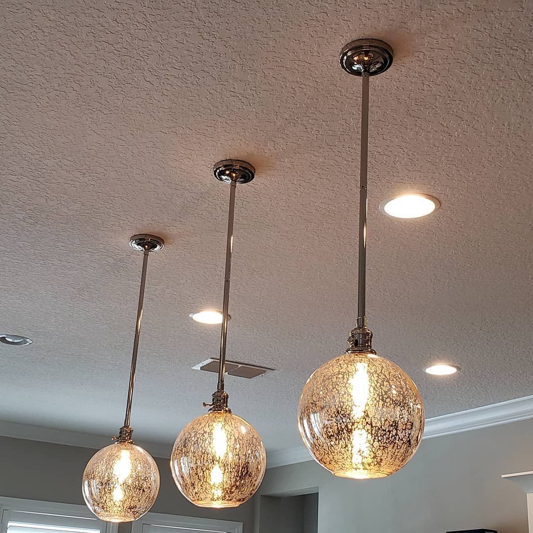 Three pendant lights with textured glass shades hang from a textured ceiling.