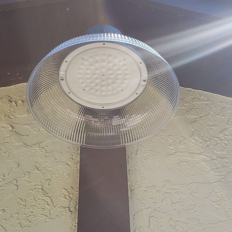 LED light fixture with ribbed, clear plastic shade mounted on a stucco wall.