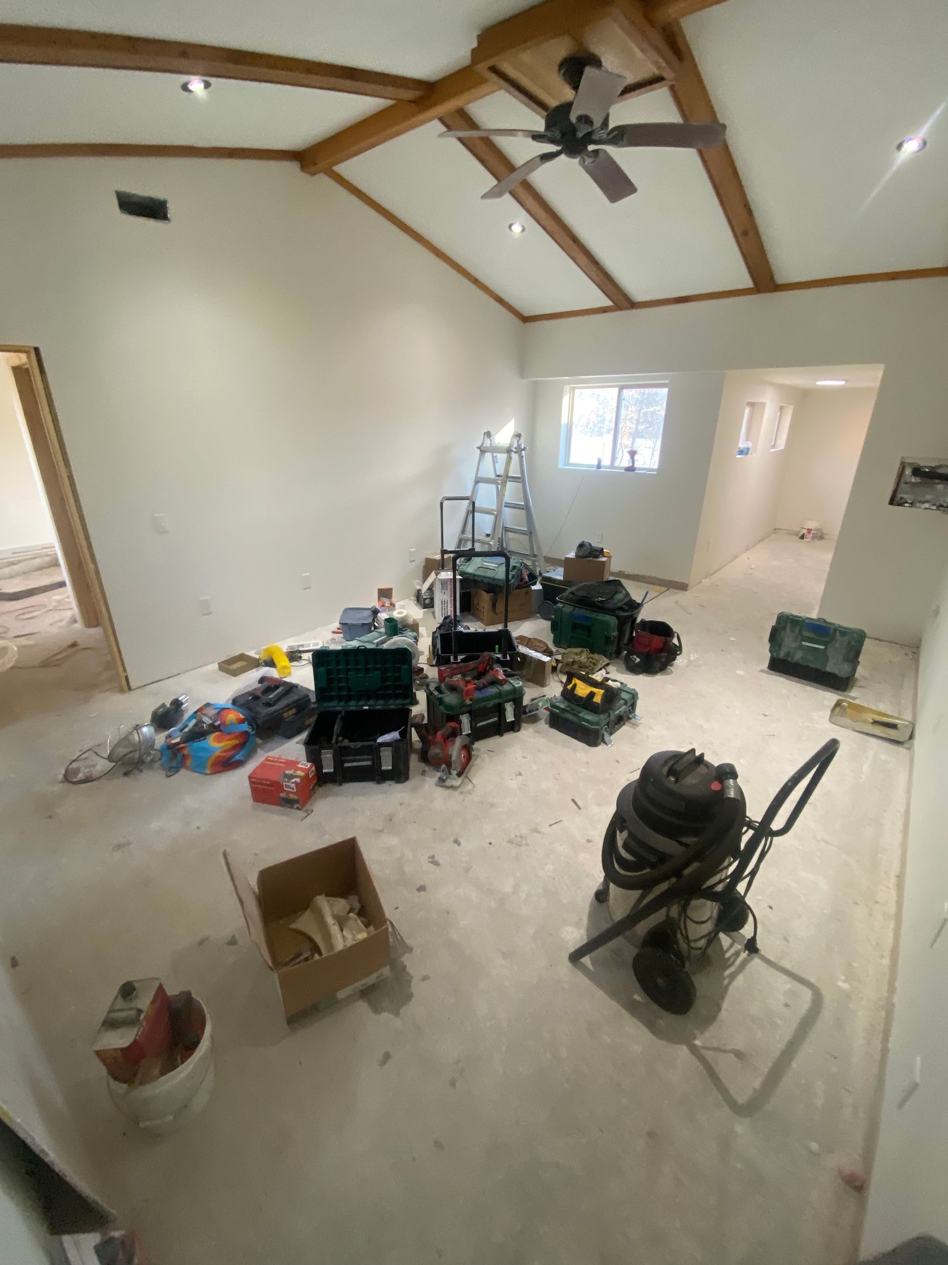 A room with a lot of tools on the floor and a ceiling fan.