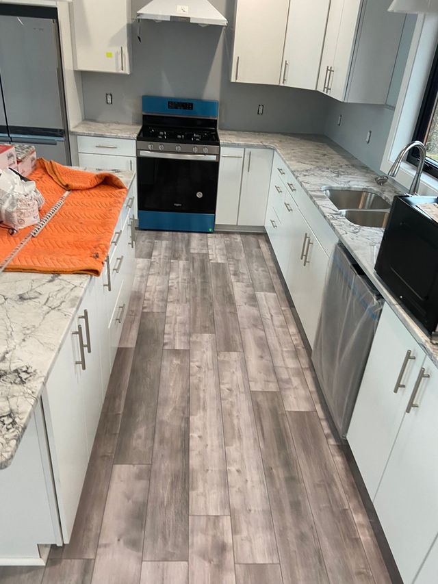A kitchen with wooden floors and white cabinets