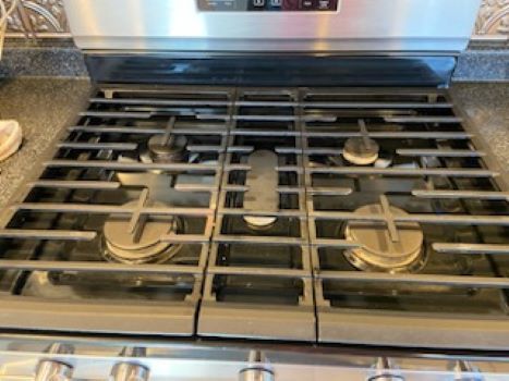 A stove top oven is sitting on top of a granite counter in a kitchen.