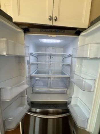 A stainless steel refrigerator with the door open in a kitchen.