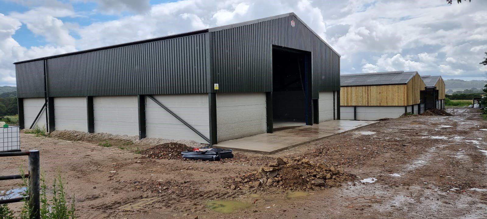 A large metal building is sitting on top of a dirt field.