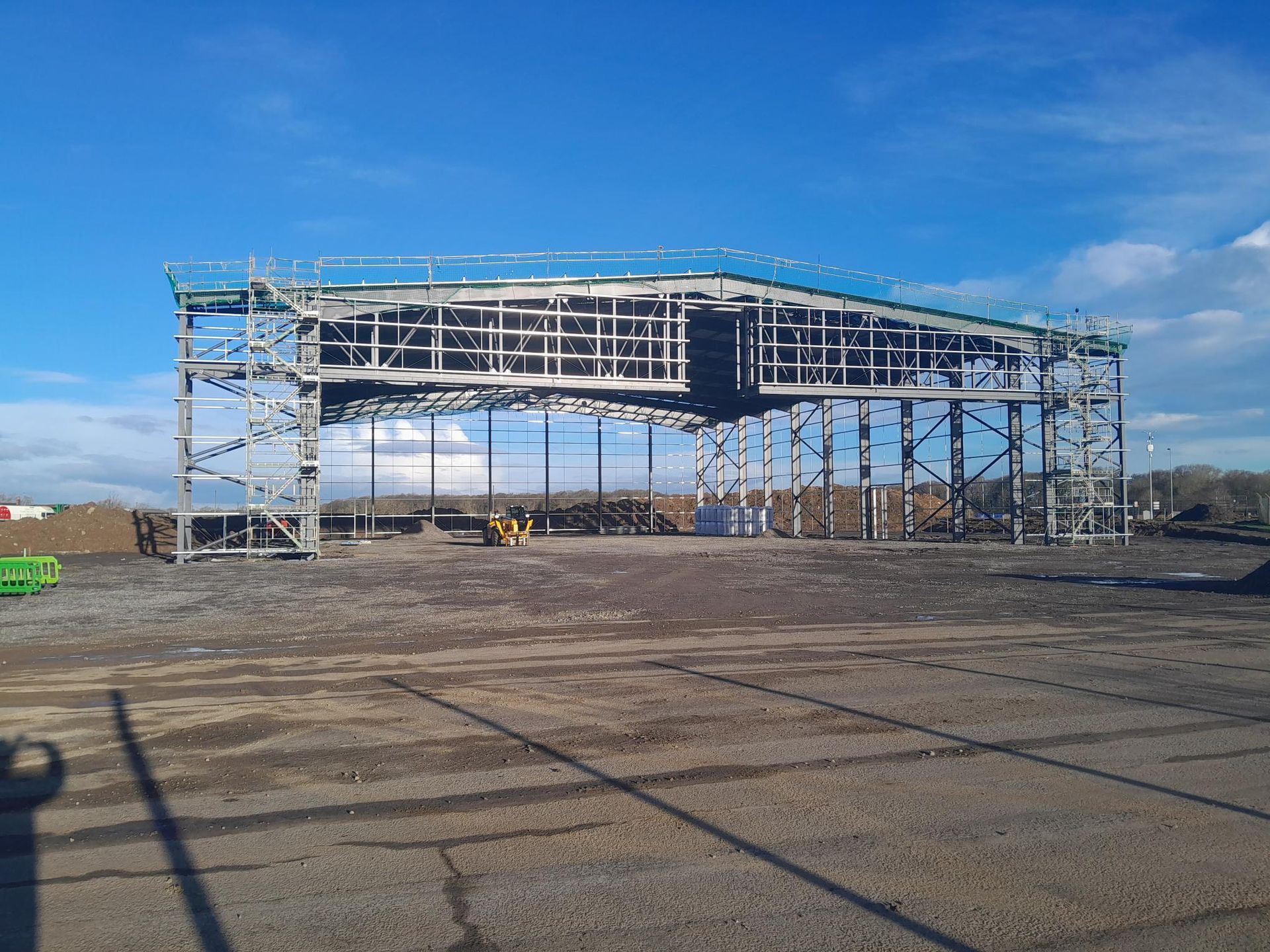 A large building is being built in the middle of a dirt field.