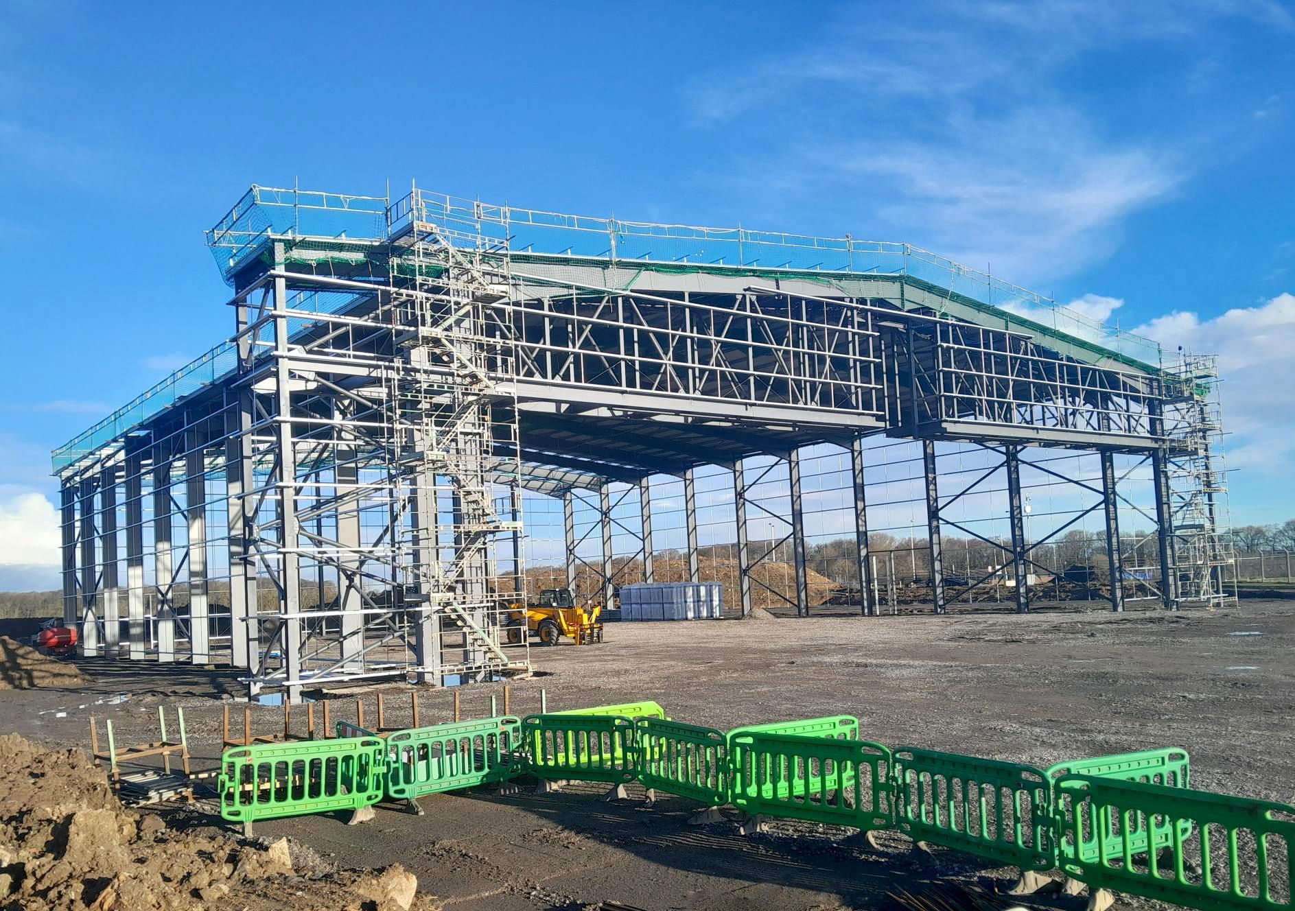 A large metal structure is being built on a dirt field.