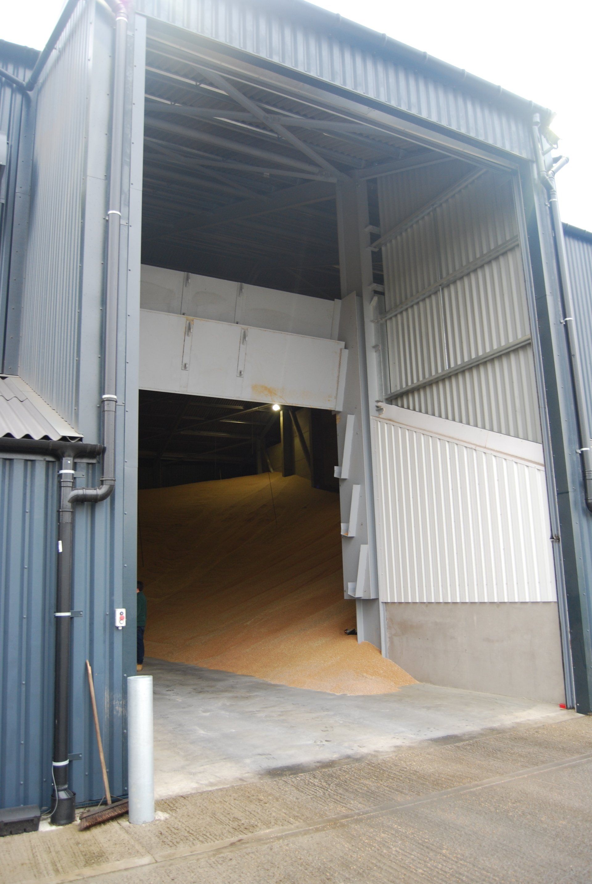 A large warehouse with a large door open filled with grain.