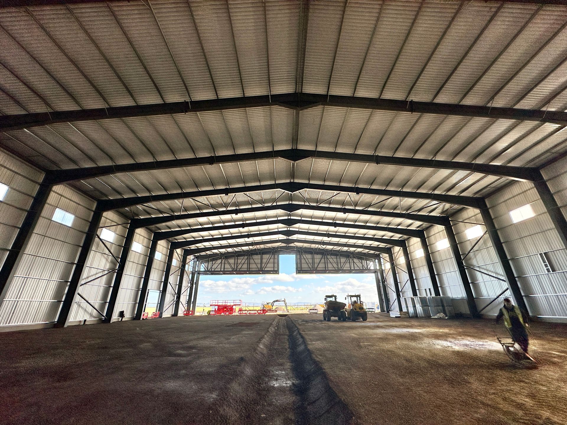 A large warehouse with a lot of windows and a lot of machinery inside of it.