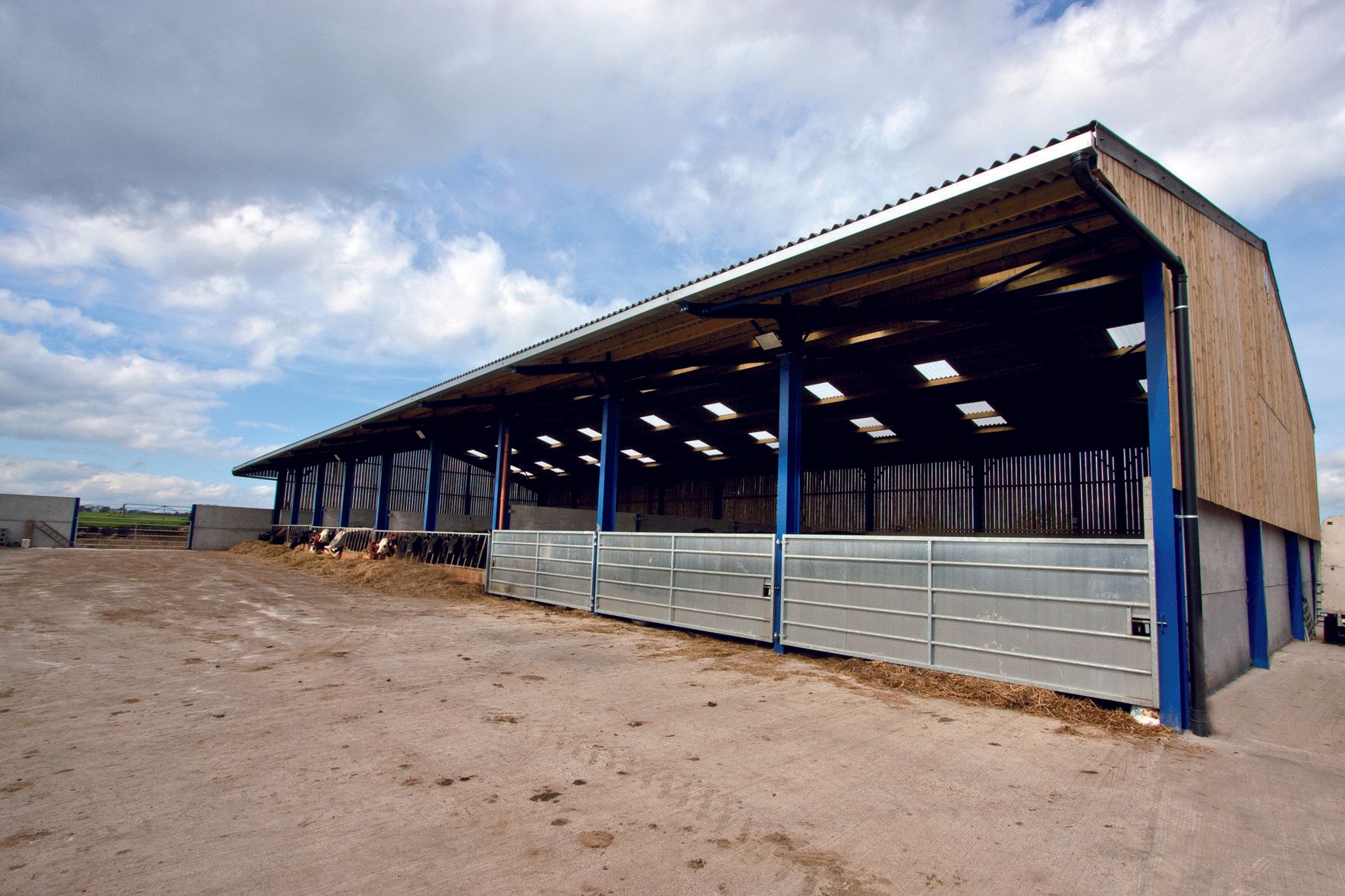 A large building with a blue roof is sitting in the middle of a field.