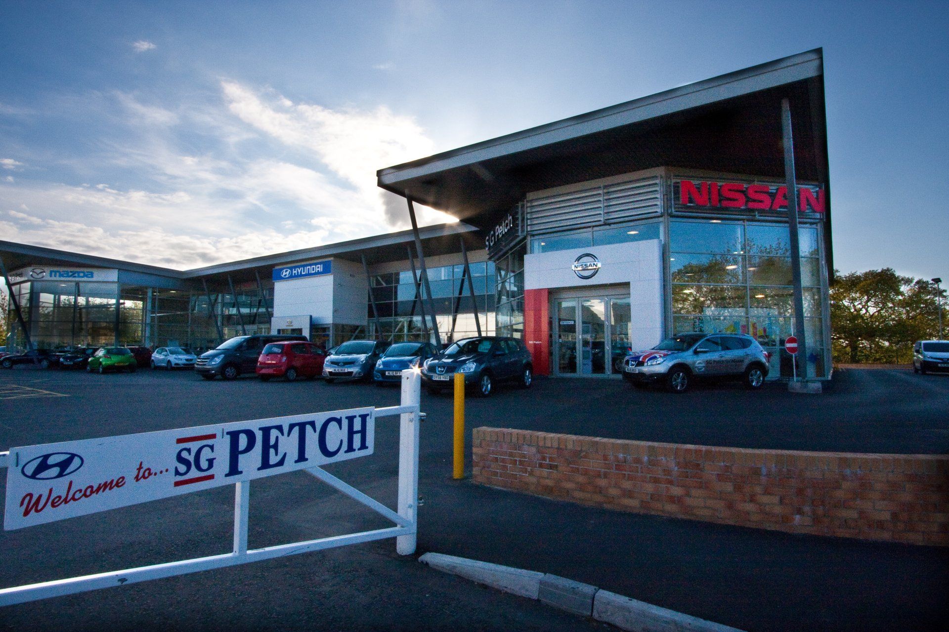 A nissan car dealership with cars parked in front of it.