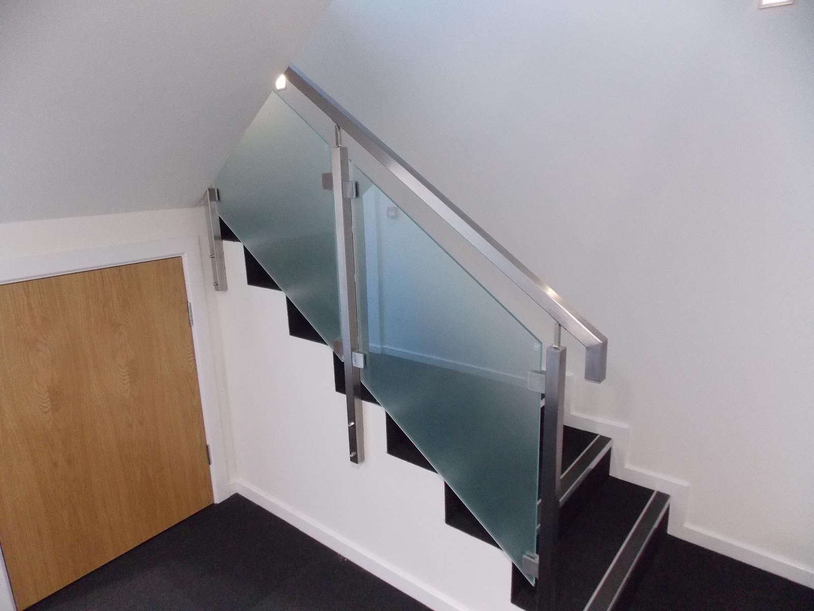 A staircase with a glass railing and a wooden door