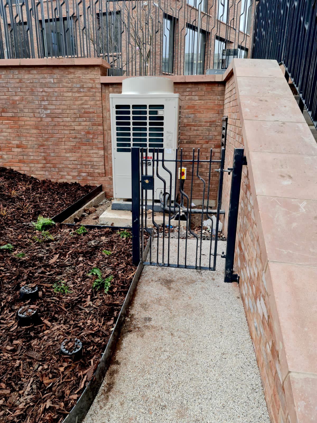 A brick wall with a gate leading to a building