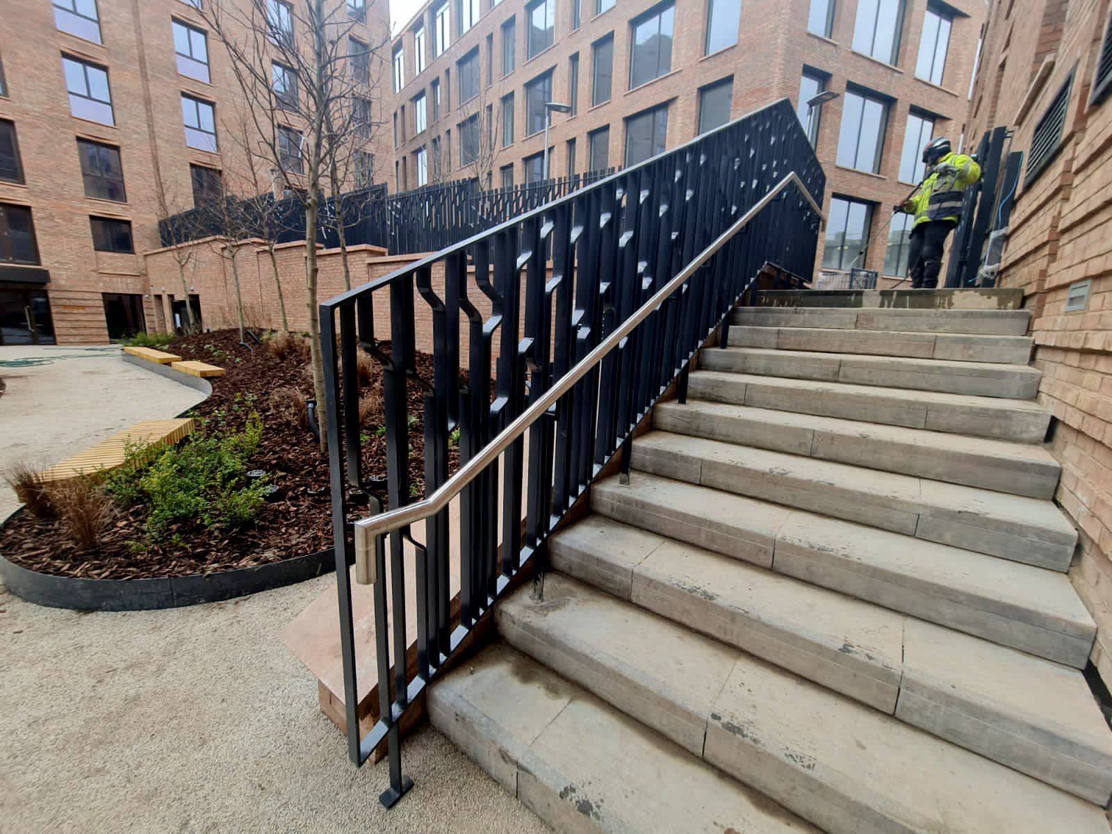 A man in a yellow vest is standing next to a set of stairs.