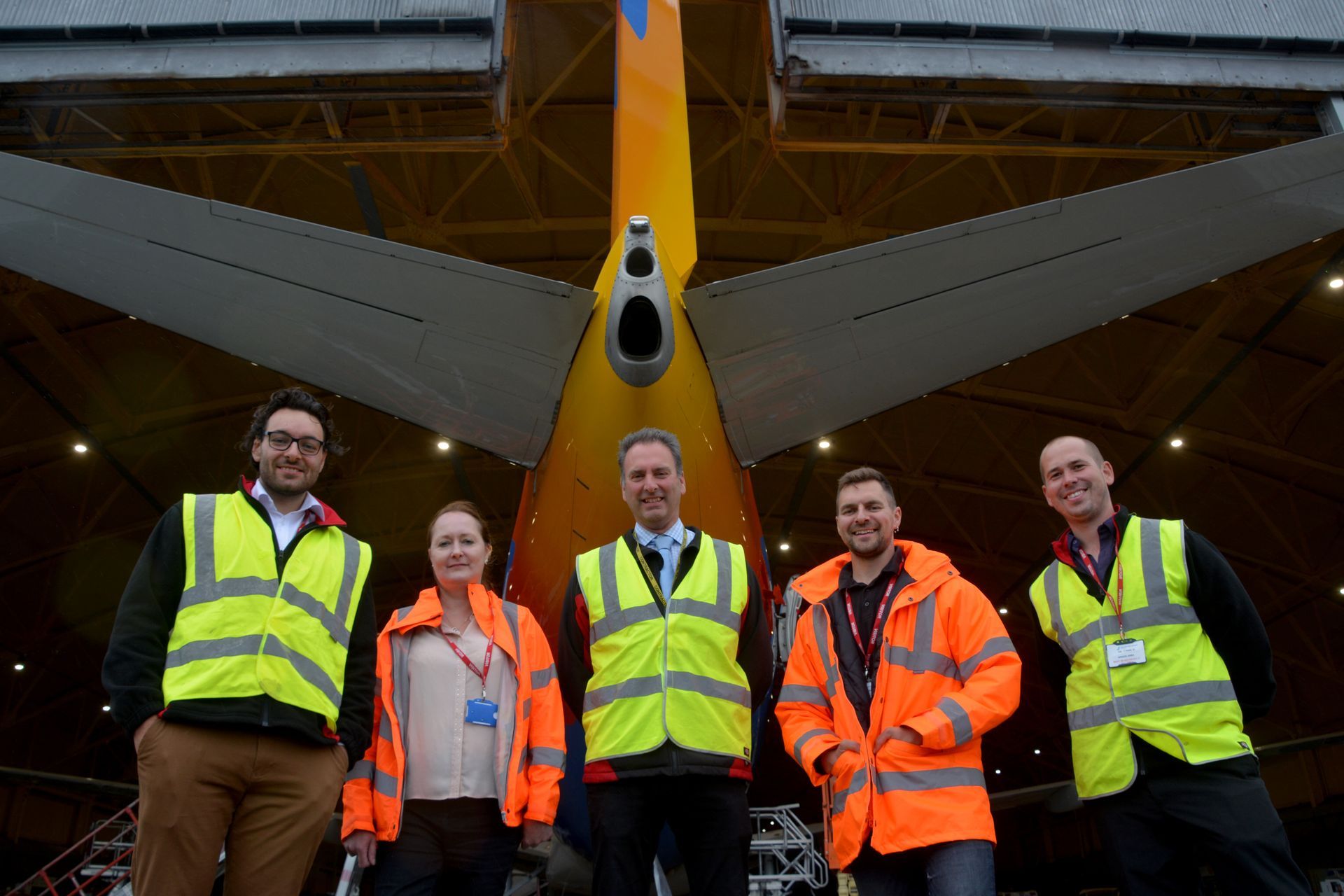A group of people in safety vests are standing in front of an airplane.