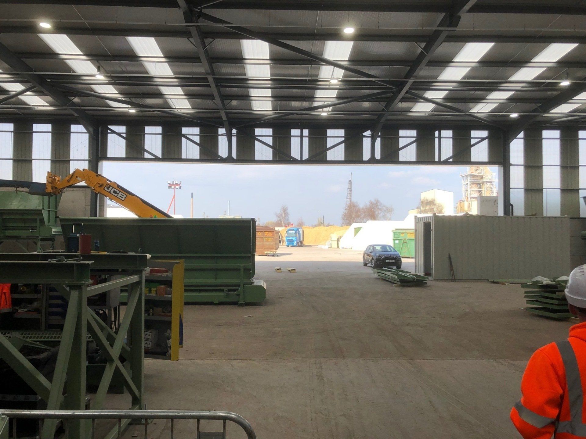 A man in a hard hat is standing in a large warehouse.