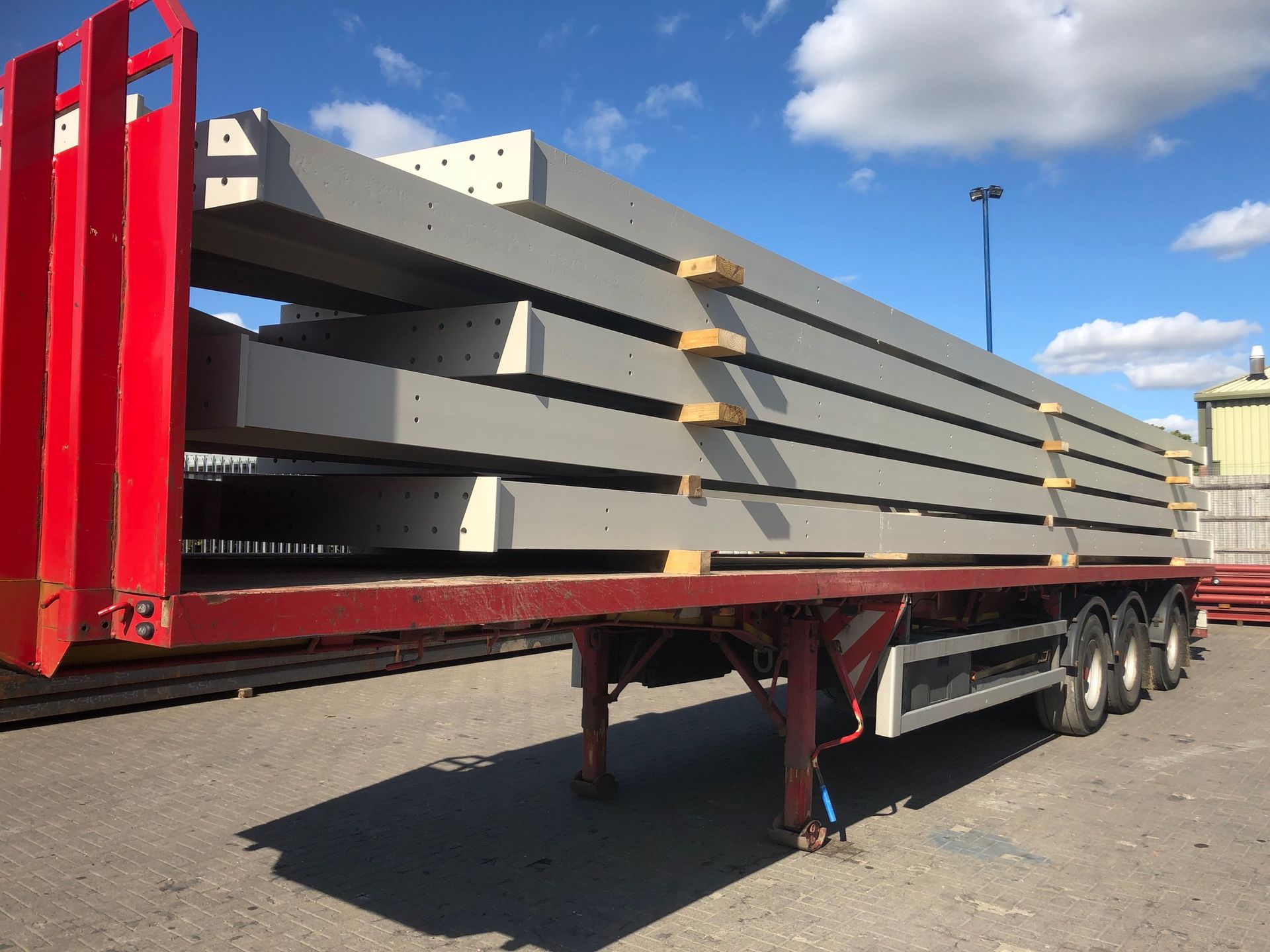 A semi truck is carrying a stack of concrete poles.