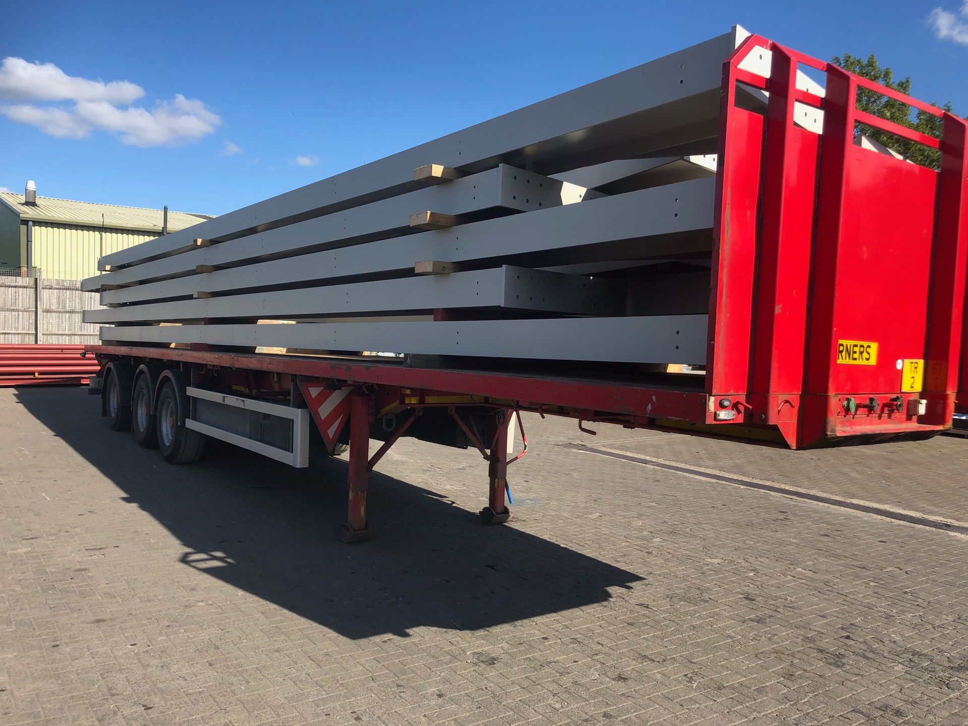 A red trailer is carrying a stack of concrete blocks.