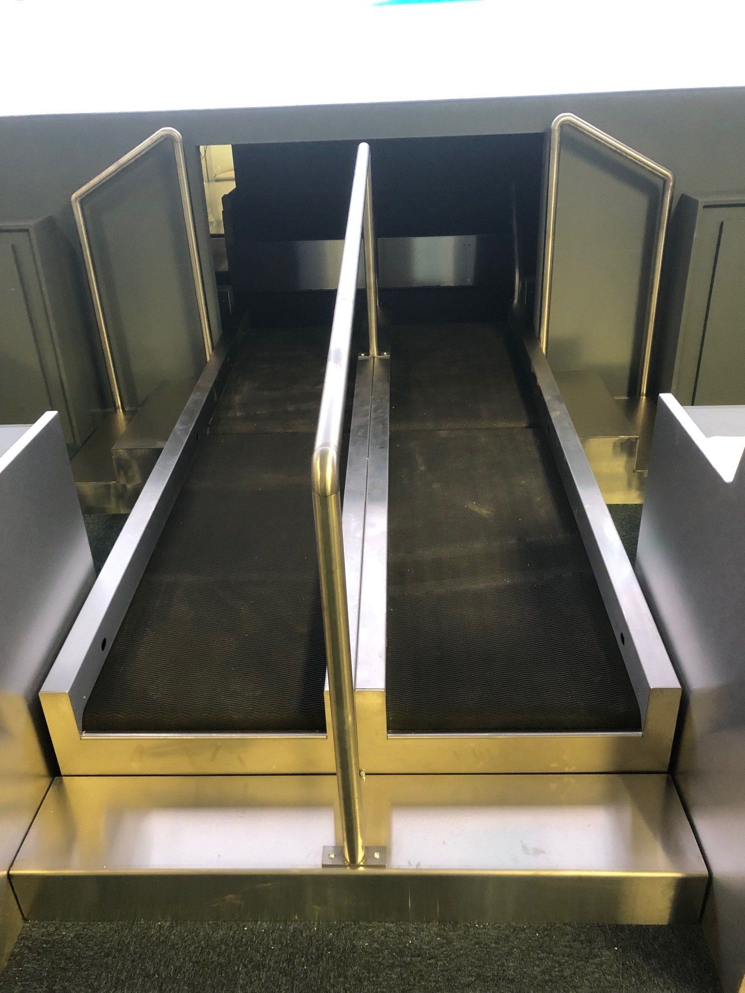 A stainless steel conveyor belt with stairs leading up to it