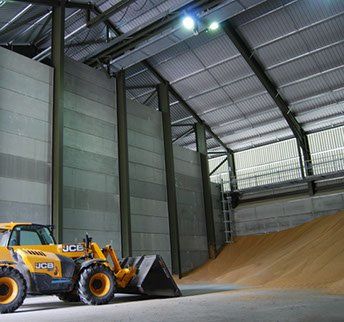 A yellow jcb tractor is parked inside of a building