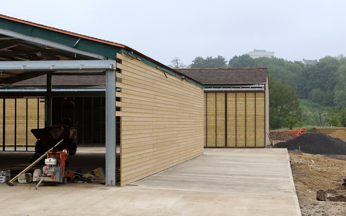 A tractor is parked in front of a building under construction.