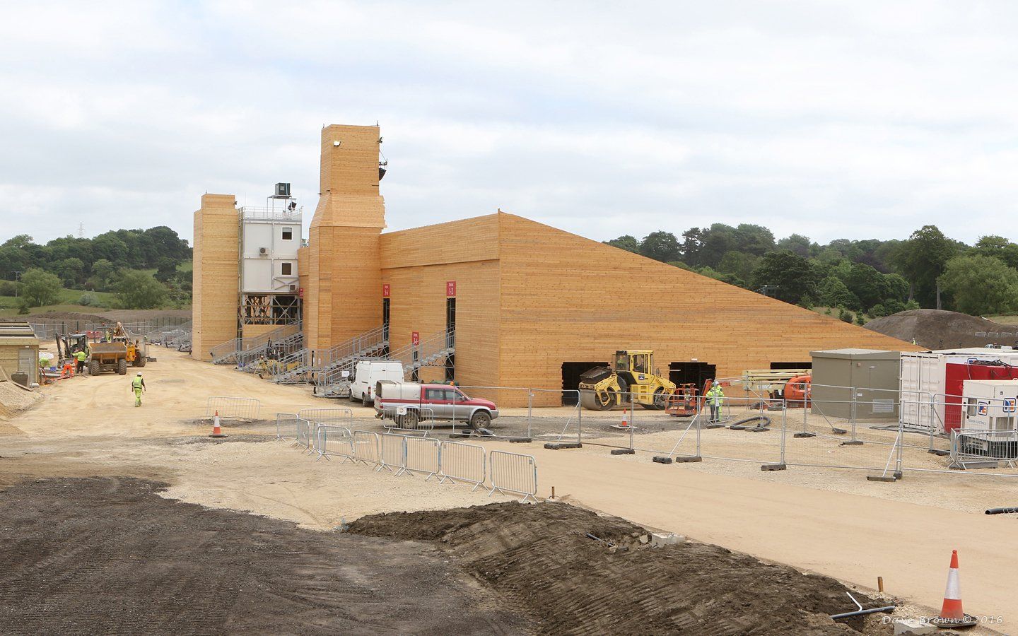 A large wooden building is being built on a dirt field.