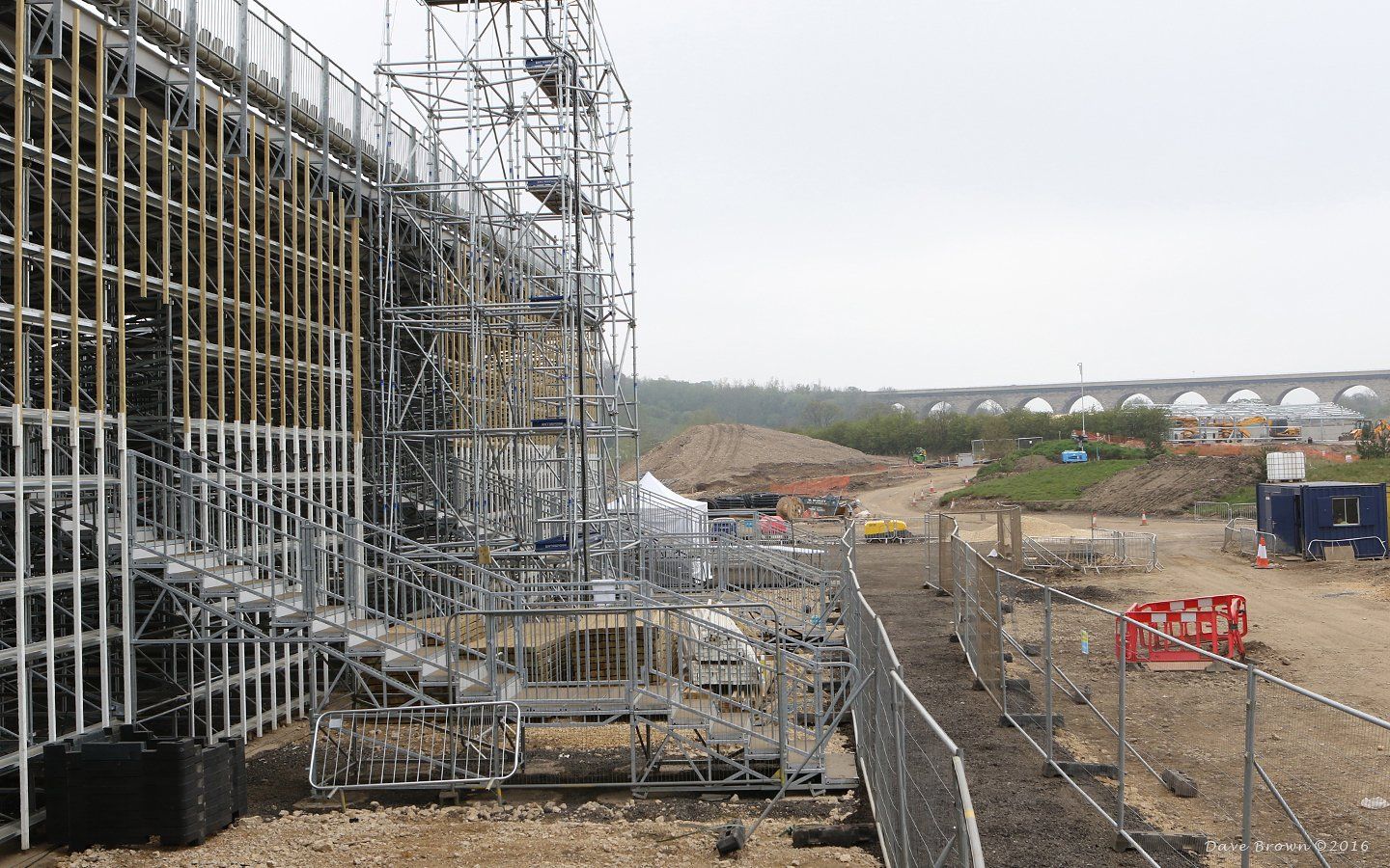 A large building is being built with scaffolding and a fence around it.